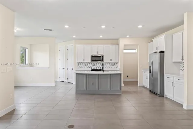 a large kitchen with a refrigerator and white cabinets