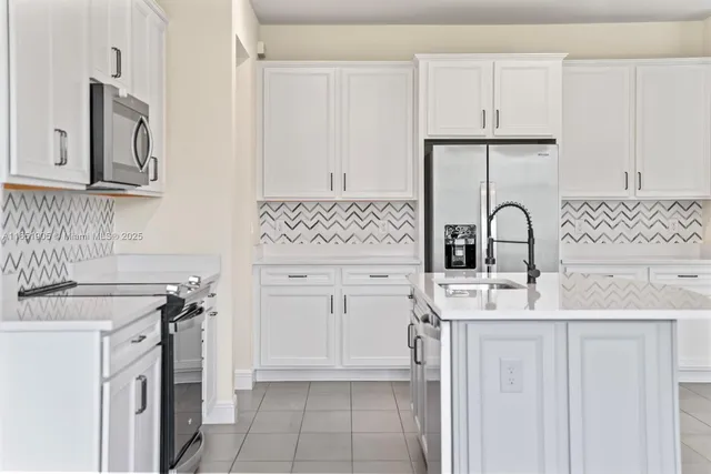 a kitchen with white cabinets and sink