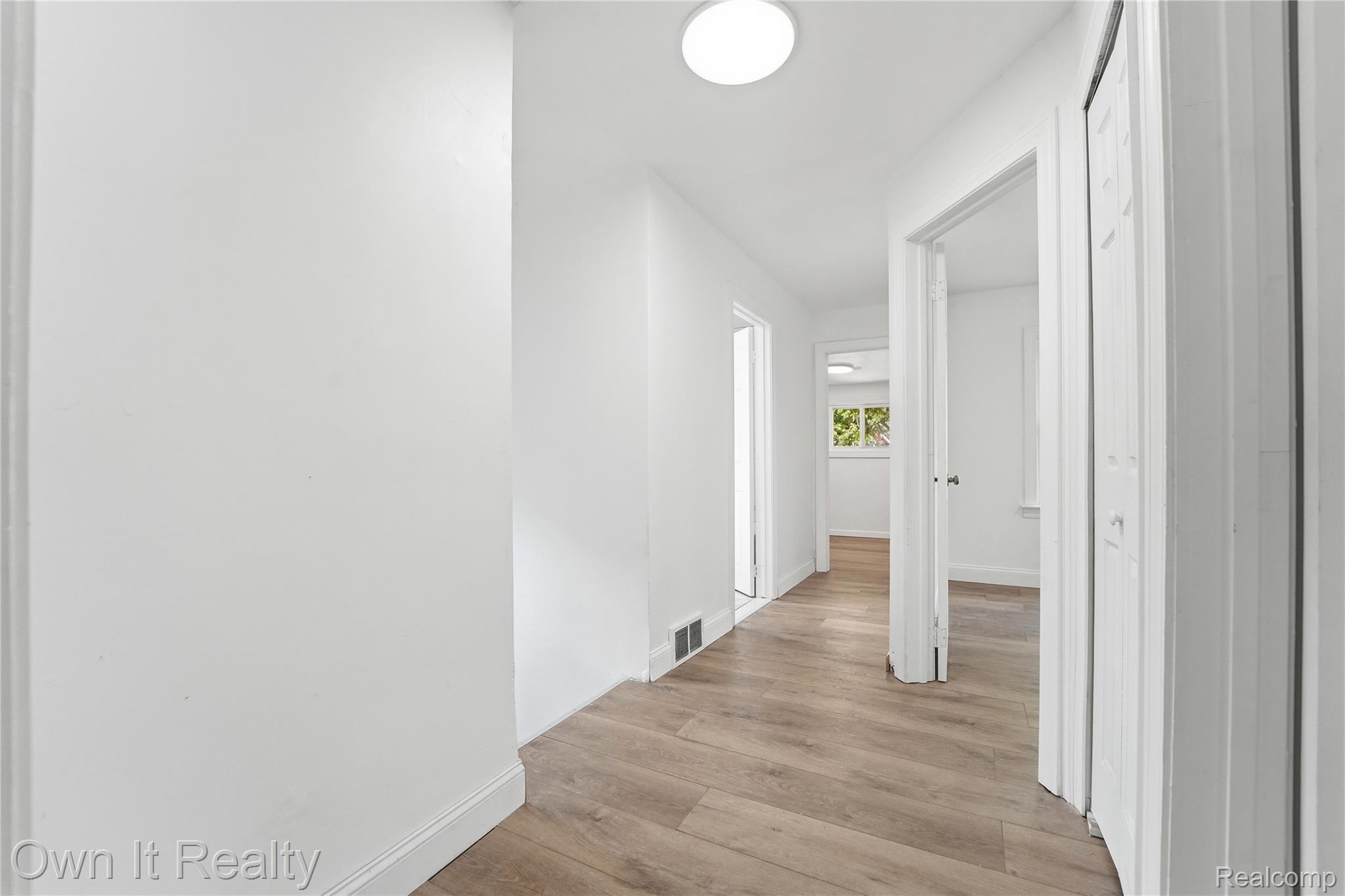 17351 Appoline Street Detroit, MI 48235 - Photo 16 of 34 Light-filled hallway featuring wood-finish flooring, white walls, white baseboards, and overhead flush-mount lighting
