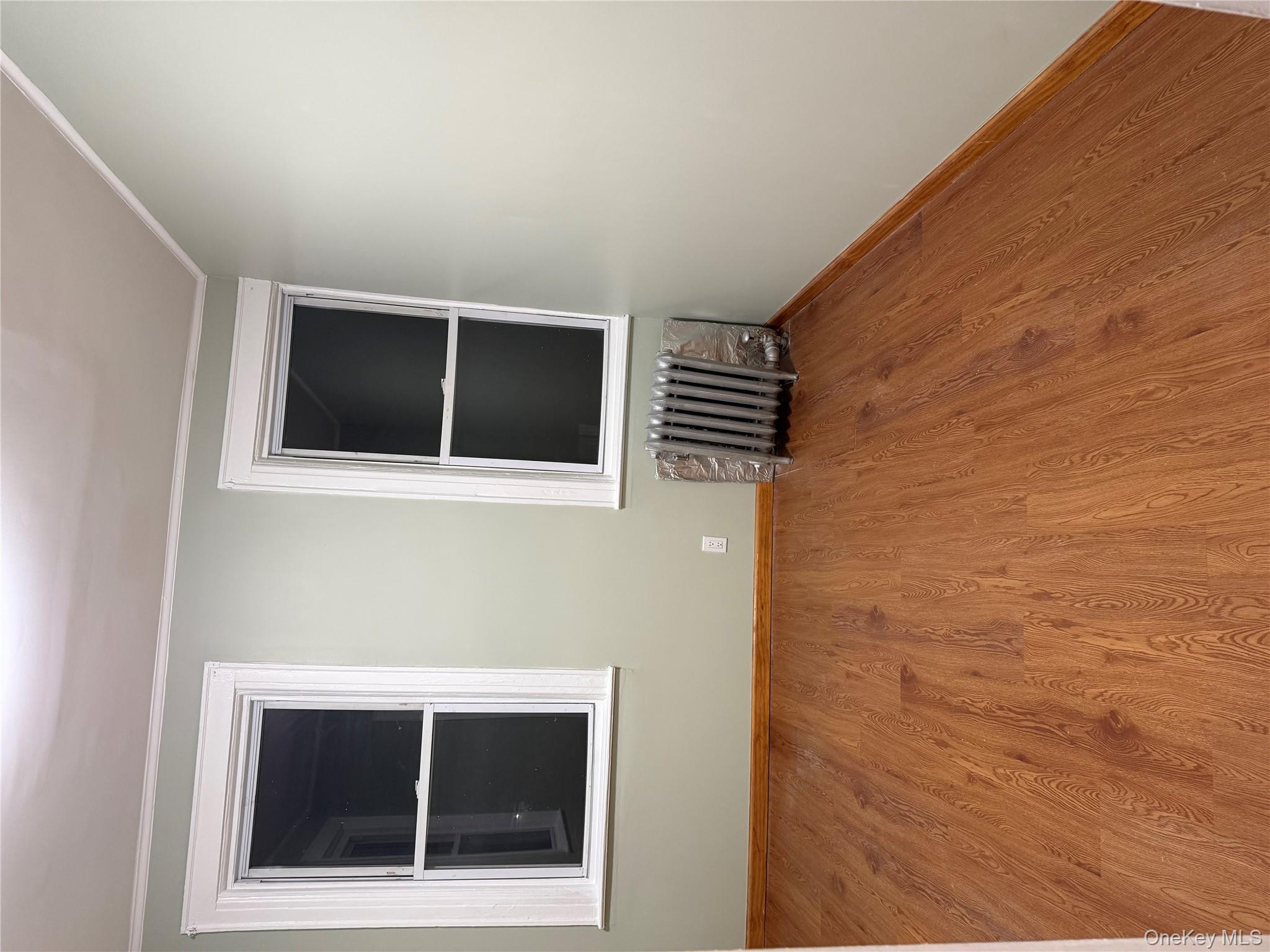 127-05 88th Avenue Queens, NY 11418 - Photo 3 of 9 an empty room with wooden floor and windows