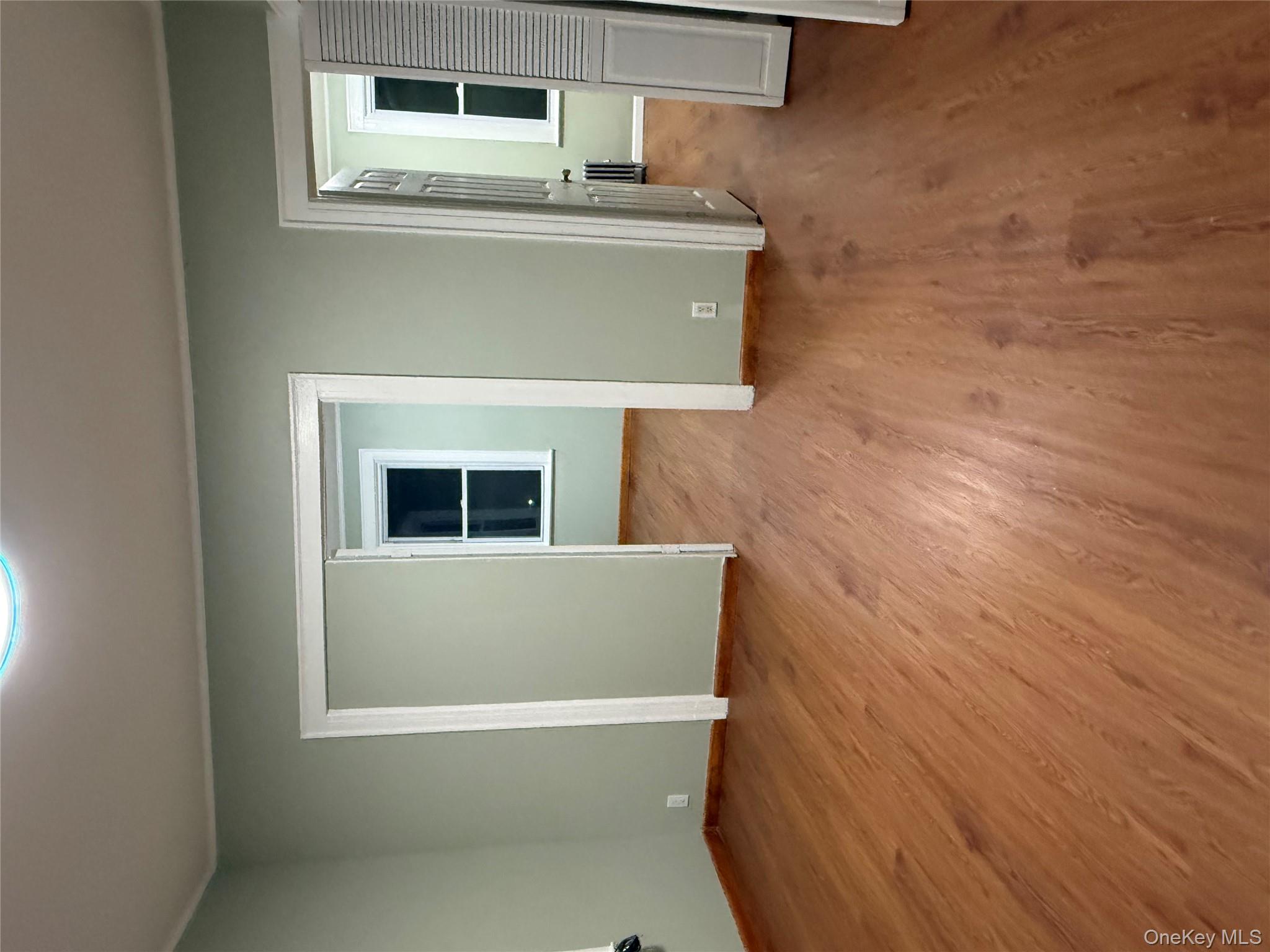 127-05 88th Avenue Queens, NY 11418 - Photo 8 of 9 an empty room with wooden floor and windows