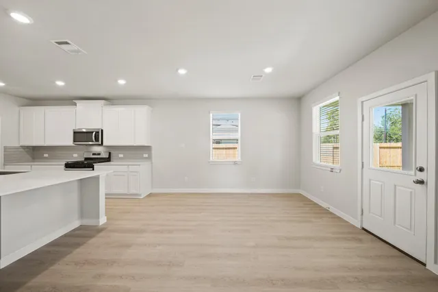 a large white kitchen with wooden floor and black appliances