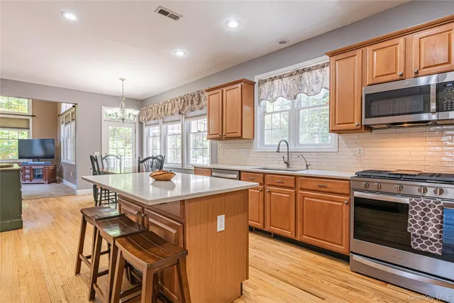 a kitchen with stainless steel appliances granite countertop a stove top oven a sink dishwasher a dining table and chairs with wooden floor