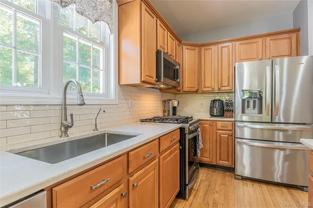 a kitchen with stainless steel appliances granite countertop a refrigerator a sink dishwasher a stove with wooden floor and cabinets