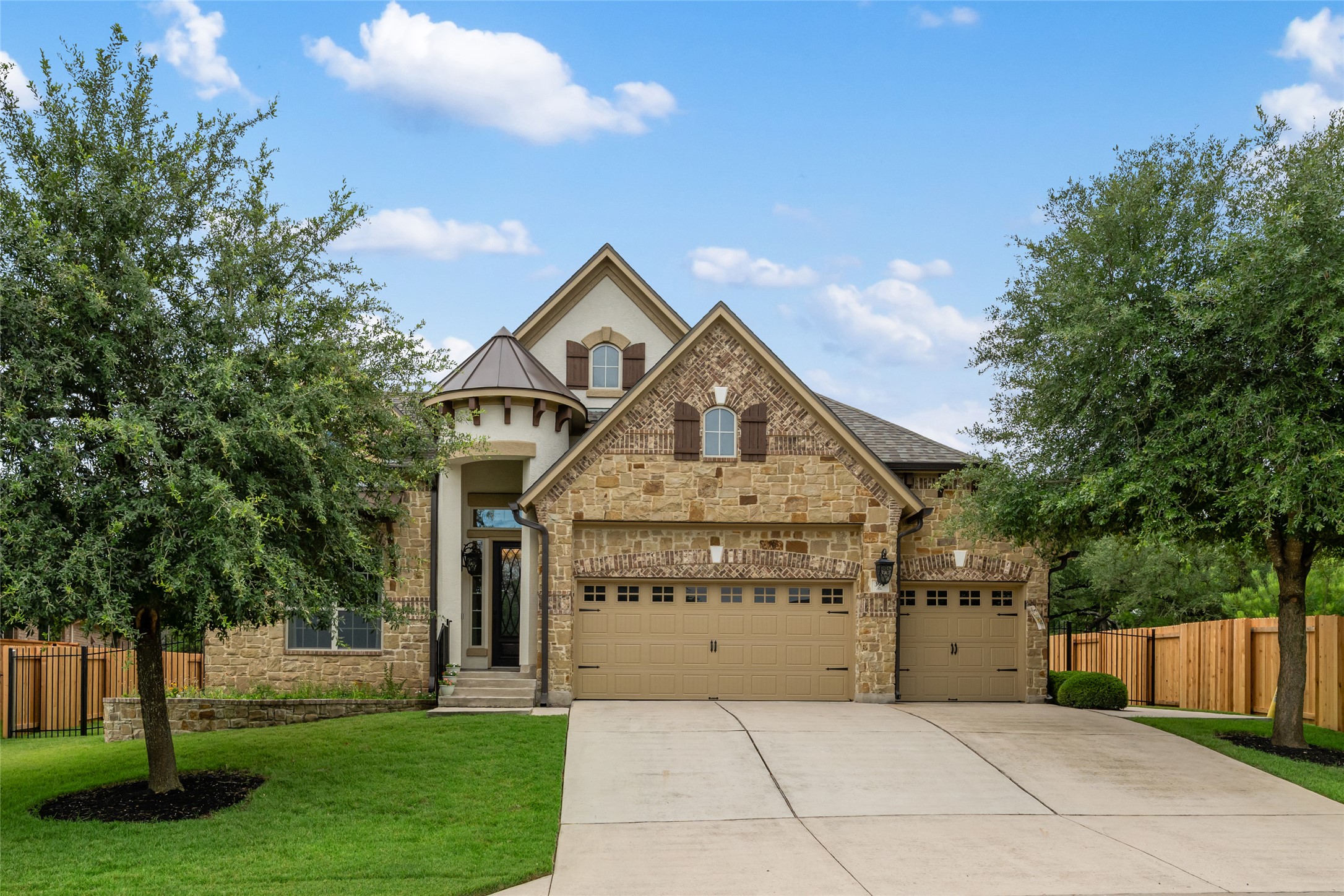 French provincial home featuring an attached garage, driveway, stucco siding, and stone siding