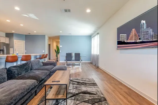 a living room with stainless steel appliances furniture a dining table and kitchen view
