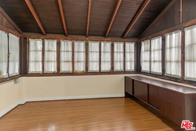 a large white kitchen with wooden floor and a large window