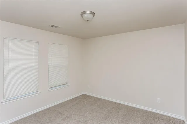 an empty room with a ceiling fan and carpet