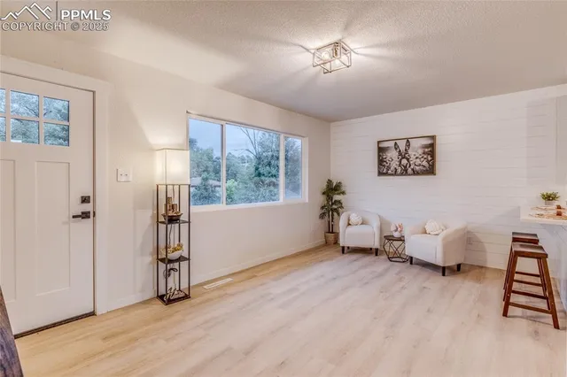 a living room with stainless steel appliances kitchen island granite countertop a stove a sink a refrigerator and white cabinets with wooden floor