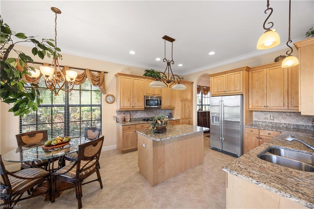 9105 Prima Way, Unit 102 Naples, FL 34113 - Photo 13 of 49 a kitchen with refrigerator and chairs
