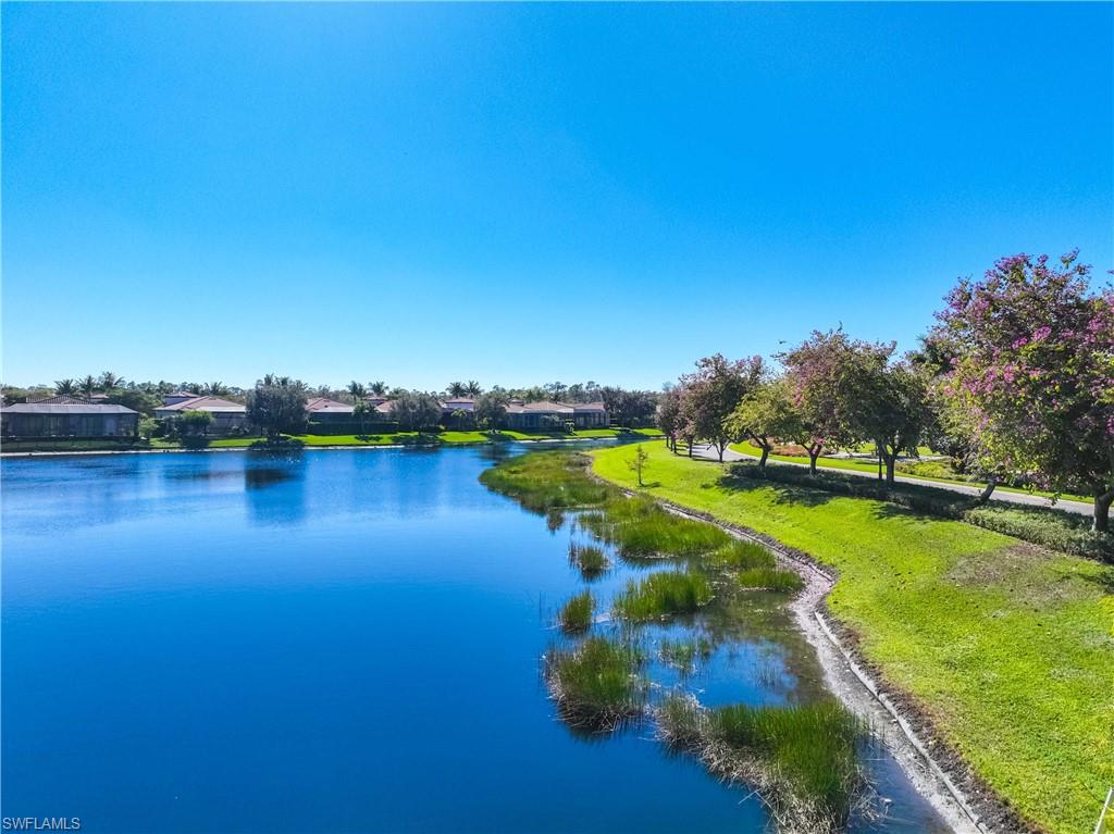 9105 Prima Way, Unit 102 Naples, FL 34113 - Photo 40 of 49 a view of a lake with houses in the back