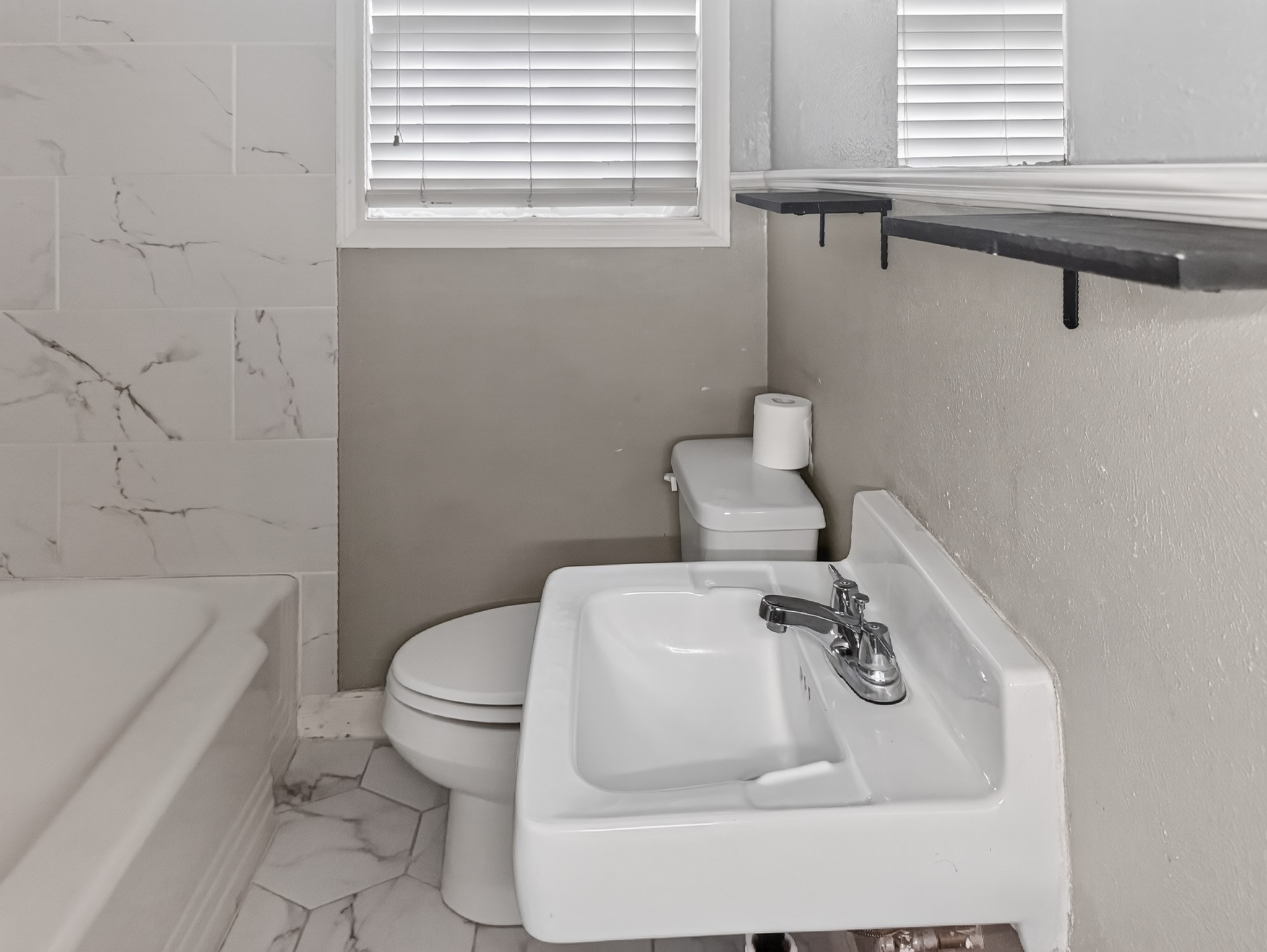 2313 Avenue L Rosenberg, TX 77471 - Photo 24 of 31 Updated bathroom featuring marble-look flooring, modern fixtures, and convenient open shelving for additional storage.