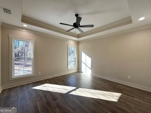 an empty room with wooden floor chandelier fan and windows