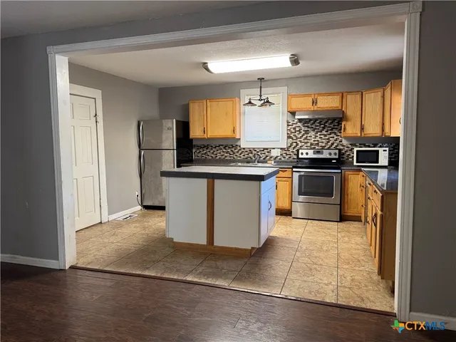 a kitchen with stainless steel appliances granite countertop a stove a sink and a refrigerator