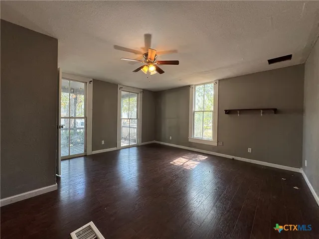 a view of an empty room with window and wooden floor
