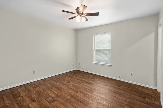 an empty room with wooden floor and ceiling fan