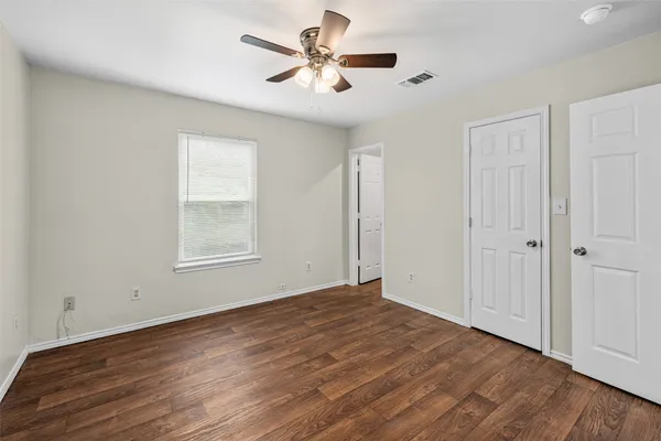 a view of empty room with wooden floor and fan