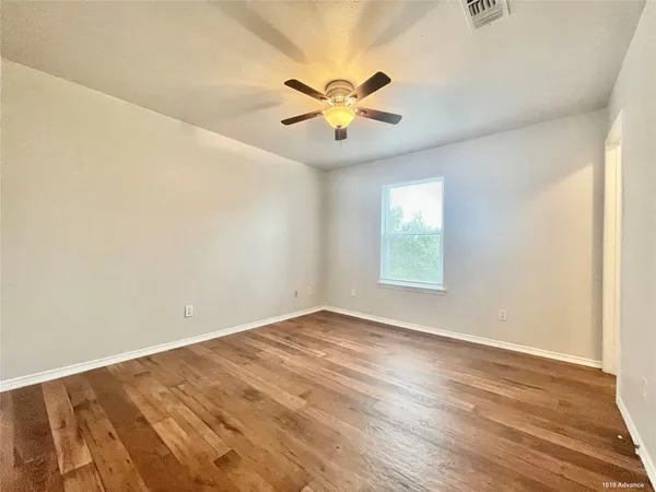 a view of an empty room with window and wooden floor