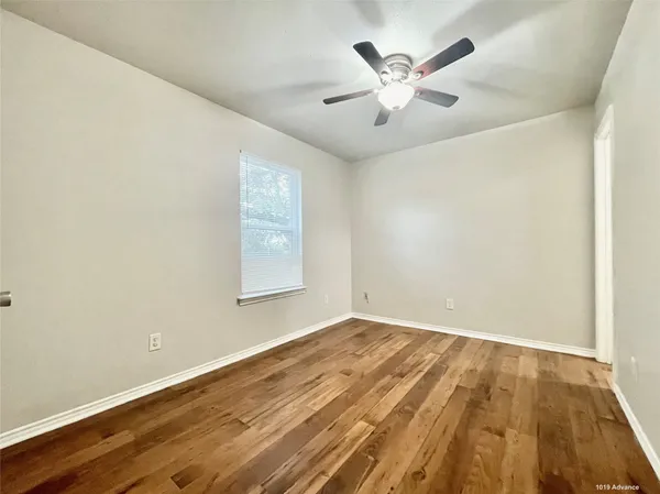 an empty room with wooden floor and ceiling fan