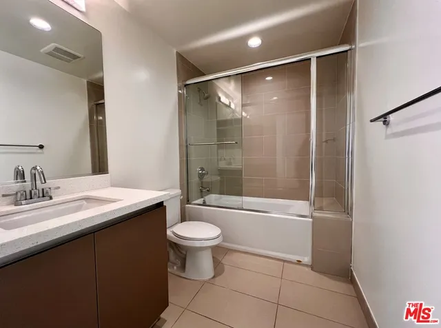 a bathroom with a granite countertop sink toilet a mirror and shower
