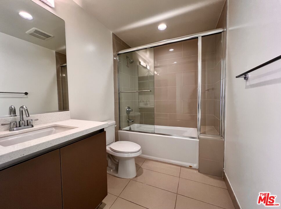 11715 Bellagio Road, Unit 104 Los Angeles, CA 90049 - Photo 15 of 26 a bathroom with a granite countertop sink toilet a mirror and shower