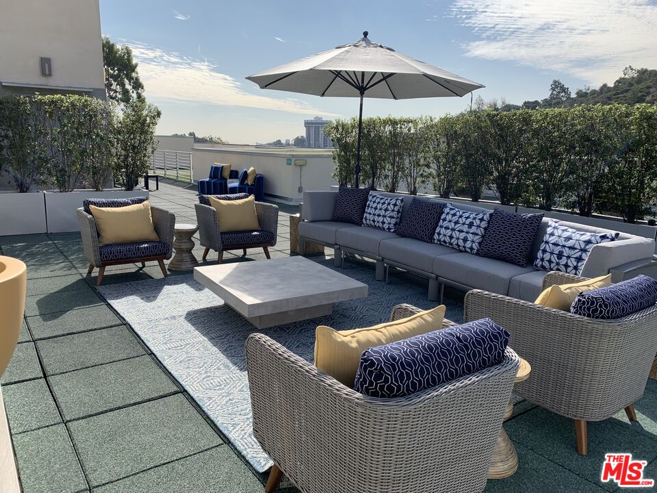 11715 Bellagio Road, Unit 104 Los Angeles, CA 90049 - Photo 20 of 26 a outdoor living space with patio furniture and a black umbrella