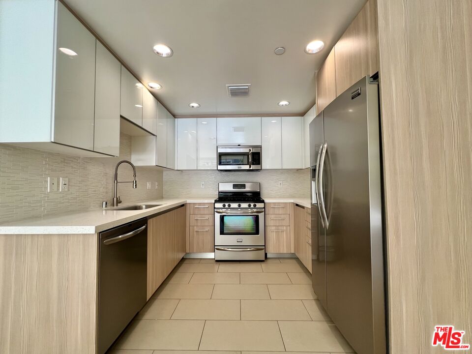 11715 Bellagio Road, Unit 104 Los Angeles, CA 90049 - Photo 5 of 26 a kitchen with stainless steel appliances granite countertop a refrigerator and a sink