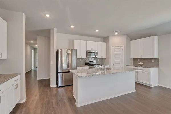 a kitchen with stainless steel appliances granite countertop a refrigerator sink and white cabinets