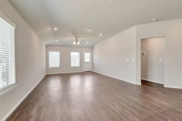 an empty room with wooden floor and windows