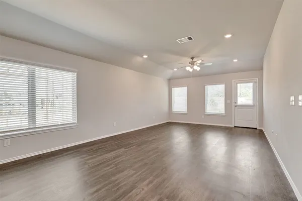 a view of an empty room with a window and wooden floor