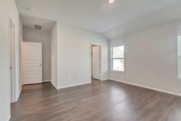 an empty room with wooden floor & windows