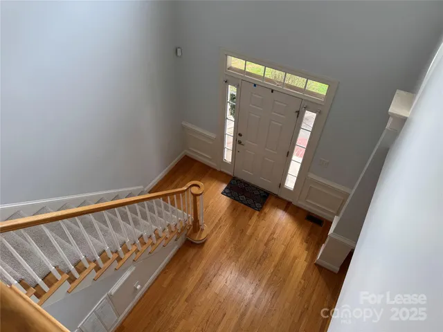 a view of a hallway with wooden floor and a bathroom