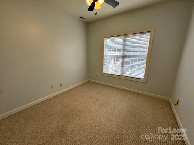 an empty room with a ceiling fan and window