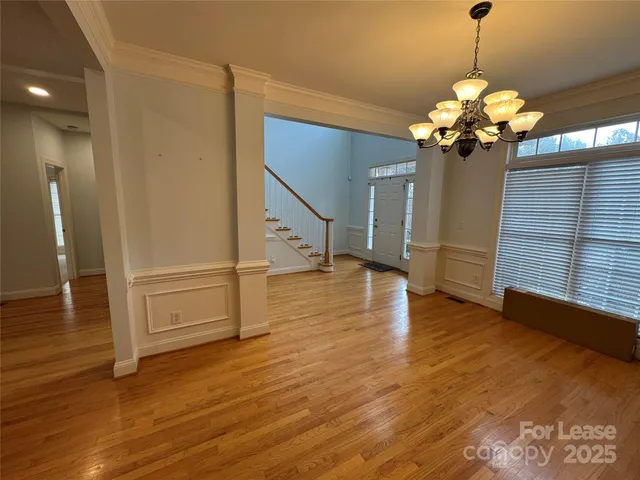 a view of a room with wooden floor and chandelier