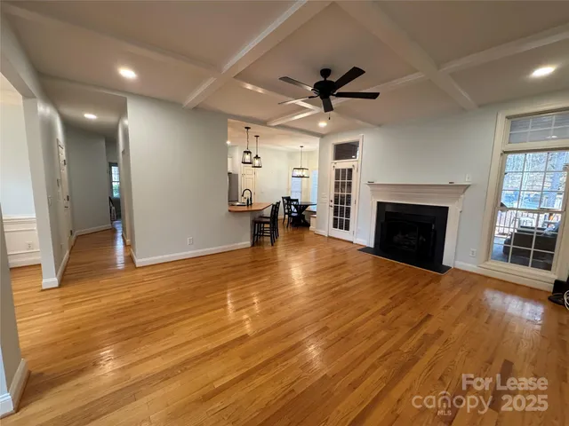a view of a livingroom with a fireplace a ceiling fan and wooden floor