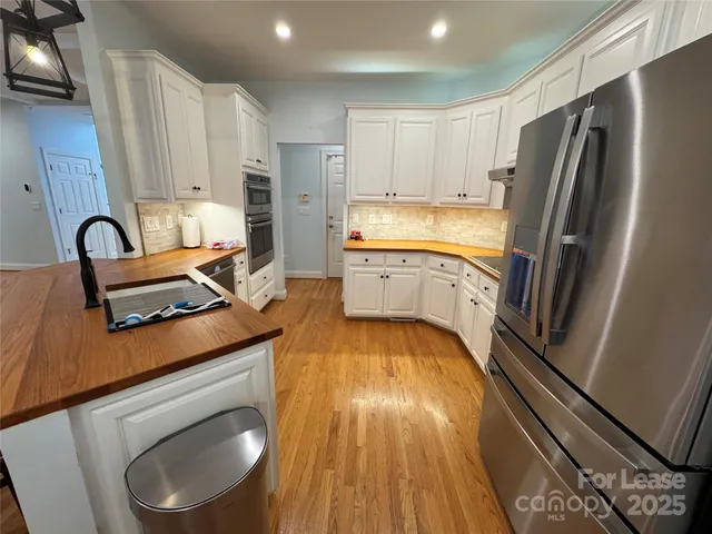 a kitchen with a refrigerator wooden floor and white cabinets