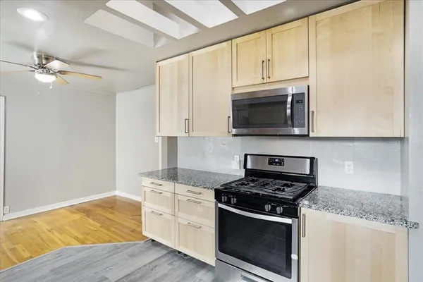 a kitchen with stainless steel appliances granite countertop white cabinets and a stove top oven