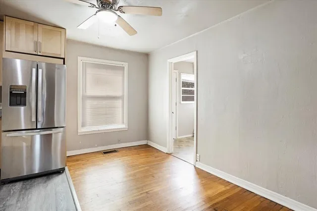 an empty room with wooden floor a ceiling fan and windows