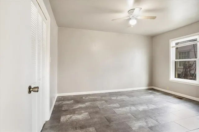 an empty room with windows and fan