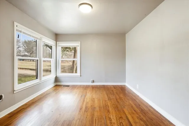a view of empty room with wooden floor and fan