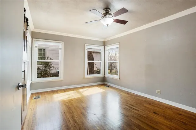a view of an empty room with a window and wooden floor