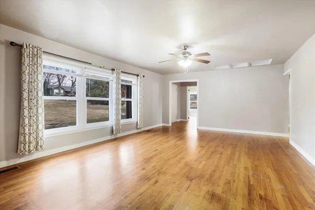 a view of an empty room with a window and wooden floor