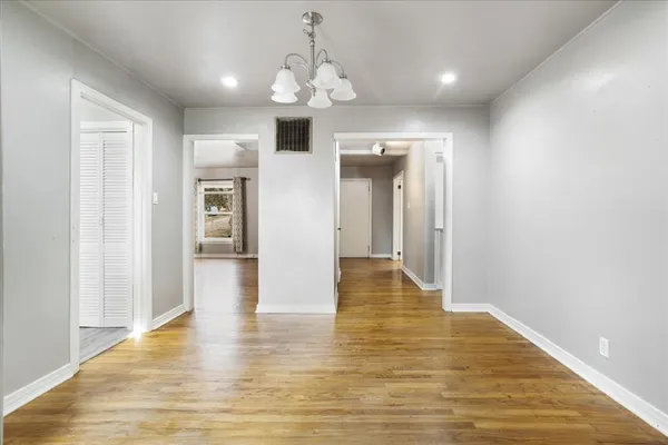 a view of a hallway with wooden floor and chandelier