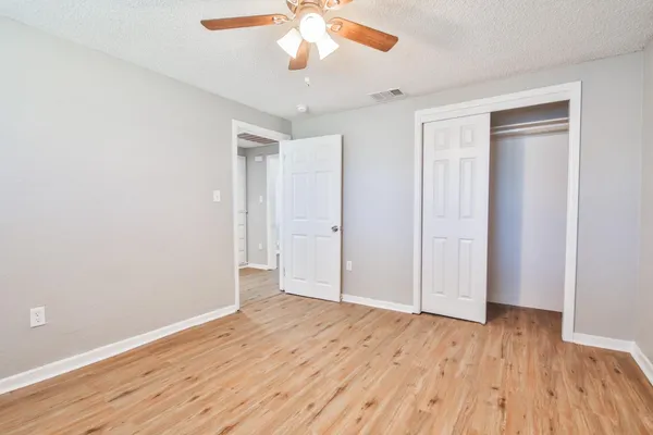 an empty room with wooden floor and a ceiling fan