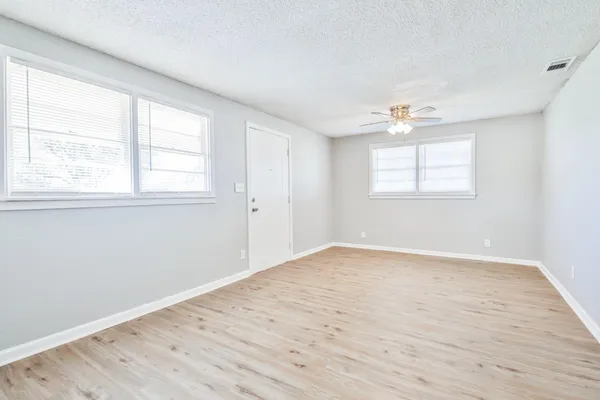 an empty room with wooden floor and windows