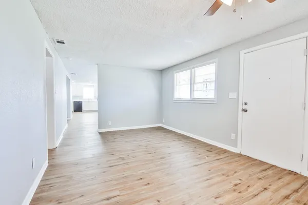 an empty room with wooden floor and windows