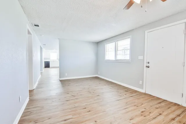 an empty room with wooden floor and windows