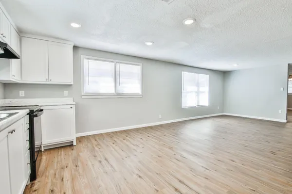 an empty room with wooden floor and windows