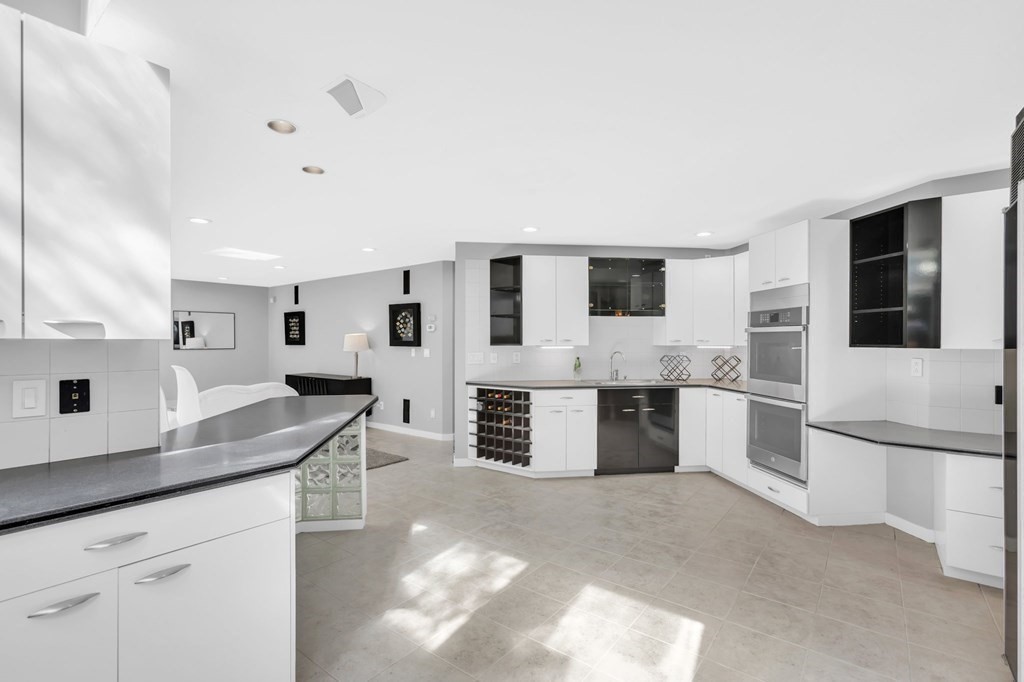 62 Chestnut Street Upton, MA 01568 - Photo 14 of 36 a large kitchen with stainless steel appliances kitchen island granite countertop a large stove top oven a sink a dining table and chairs