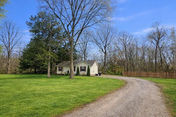a front view of house with yard and trees all around